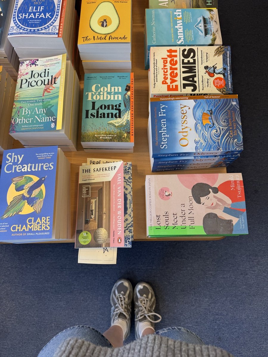Rebecca’s trainers beside a table piled with novels in a Lyme Regis bookshop