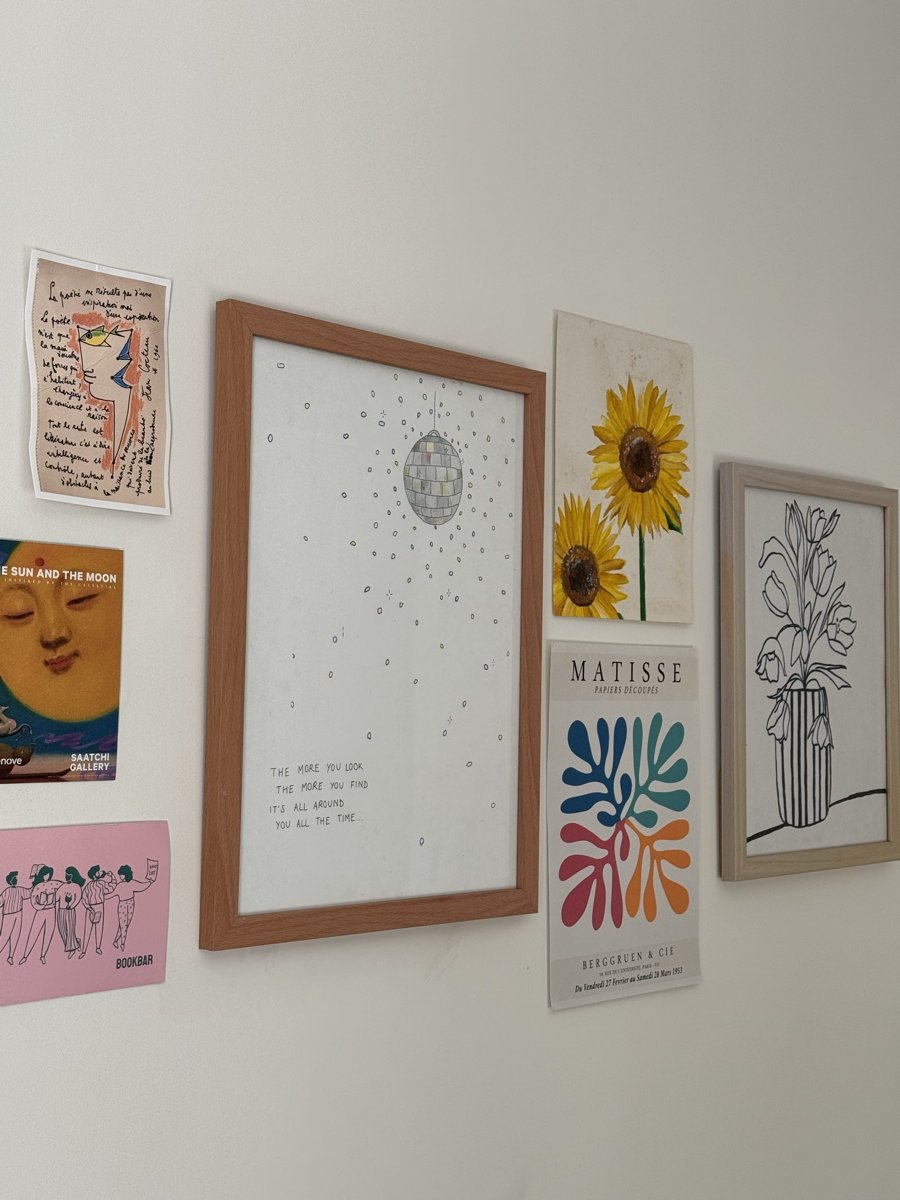A wall of framed prints, including sunflowers, a Matisse poster and a framed poem