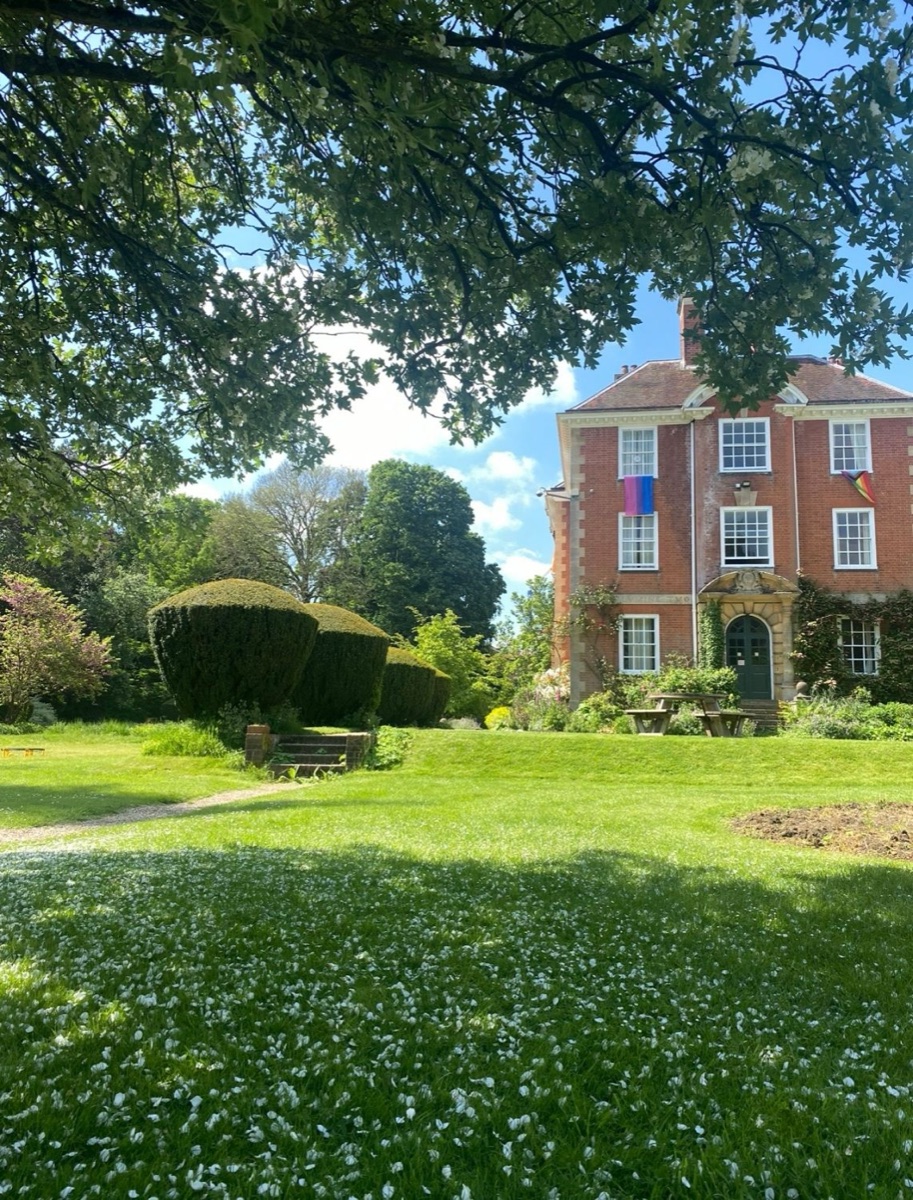 Lady Margaret Hall, Oxford: a red-brick building behind a lawn scattered with blossom